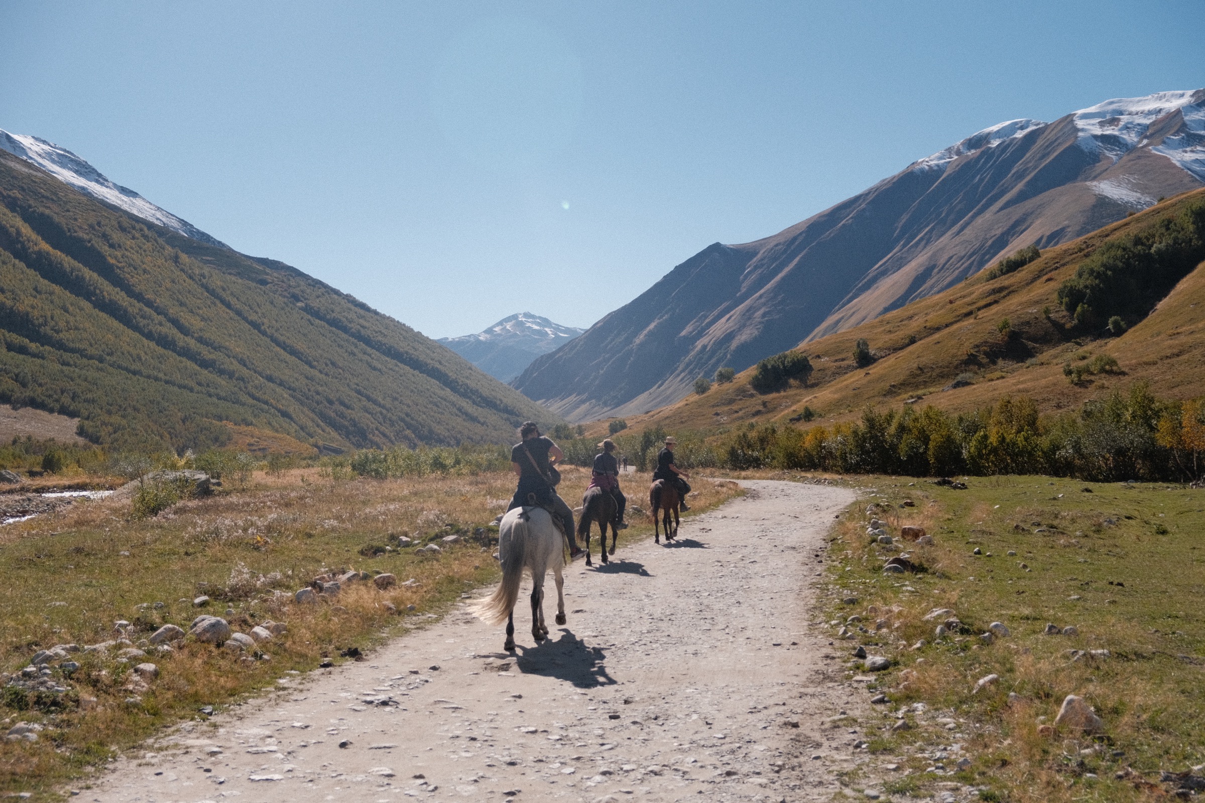 Riders on horseback following a mountain valley trail near Ushguli, Svaneti, Georgia.